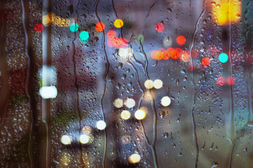 raindrops on the window and multi colored street lights at night background