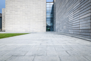 Fototapeta premium Empty square floor pavement leading to the entrance of a modern architecture office building exterior with grey walls.