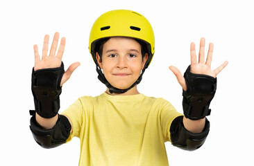 Little boy is wearing a yellow helmet and wrist protection and is looking at camera on pure white...