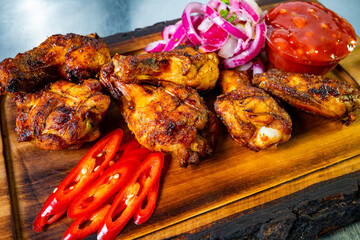 Delicious grilled chicken wings served with sauce and onions