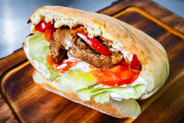 Delicious chicken sandwich with fresh vegetables on wooden board