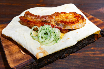Grilled pork rib served with fresh herbs on flatbread