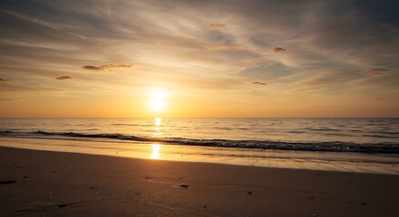 Obraz premium Beach at Golden Hour: Gentle Waves Reflecting Setting Sun, Warmth and Tranquility on Horizon