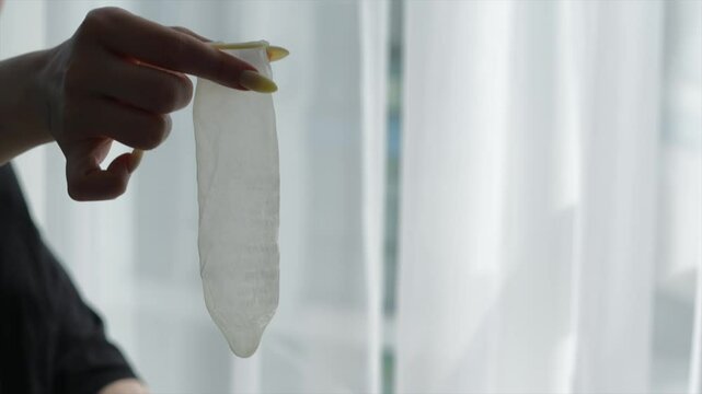 control during sex.
Safe sex and protection from bacteria and sexually transmitted diseases.
HIV infection.
Condom in women's hands.
Intimate objects in hands.
Adult games