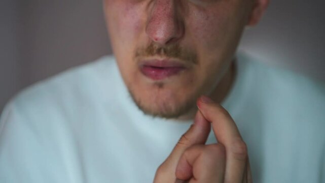 A man is worried and bites his nails.
Nervous state and fingers in the mouth.
Nail biting close-up.
Hand and nail hygiene.