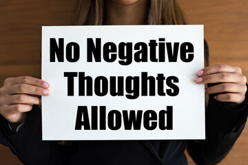 No negative thoughts allowed. Woman holds a white page, with black letters. Advice, agreement, negative emotion, thinking, tolerate, inspiration, rejection, forbidden.