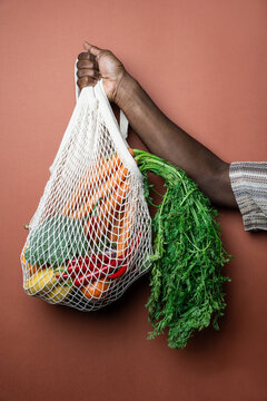 African man hand holding a reusable bag with fresh vegetables