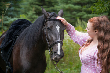 Obraz premium Woman gently caressing her horse in a green forest setting