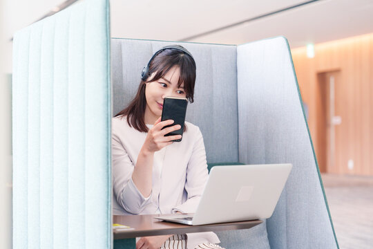 リモート会議をサボってスマホを使う若いビジネスパーソン