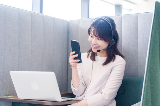 リモート会議をサボってスマホを使う若いビジネスパーソン