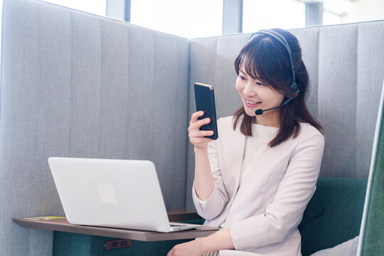 リモート会議をサボってスマホを使う若いビジネスパーソン