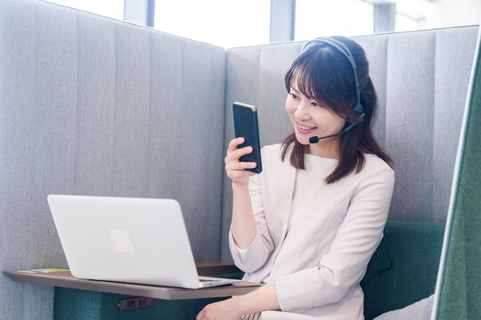 リモート会議をサボってスマホを使う若いビジネスパーソン
