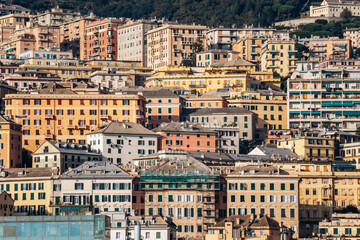 Genoa, Italy - September 22, 2024: Colorful hillside facades and layered historic buildings rise above the port waterfront with boats and greenery.