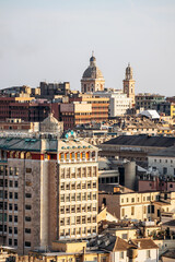 Fototapeta premium View of Genoa's rooftops at sunset, showcasing the city’s historic skyline and warm golden light.
