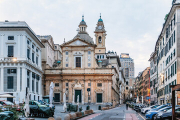 Naklejka premium Genoa, Italy - September 22, 2024: Baroque facade of Basilica di San Siro with statues and green doors faces lively square in city center.