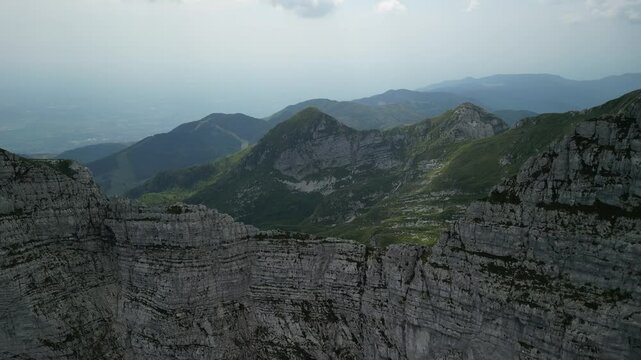 drone descending on rocky mountains under a cloudy sky in summer in Levico Terme, Italy