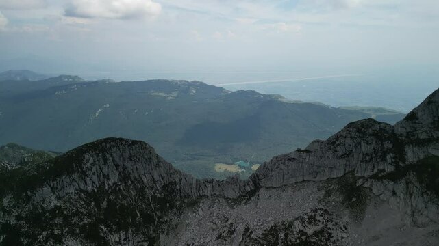 Drone landscape view of green valley with rocky mountains under cloudy sky in Levico Terme, Italy