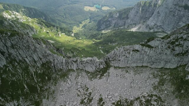 Drone landscape view of green valley with rocky mountains under cloudy sky in Levico Terme, Italy