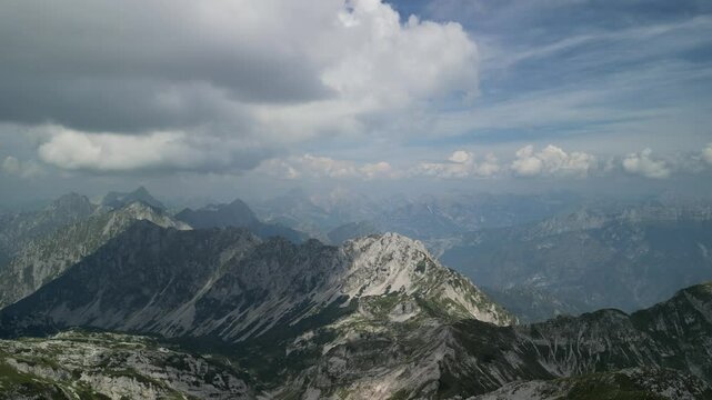 view from a drone flying over rocky mountains under a cloudy sky in summer in Levico Terme, Italy