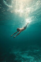 A diver explores the depths of the ocean with sunlight shining through the water.