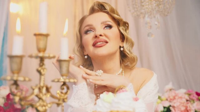 sexy blonde woman queen beauty face blue eyes pink lips make-up, lady sitting at dinner table with burning candles dessert cakes pies cup tea. Fantasy Girl princess Victorian style room vintage dress