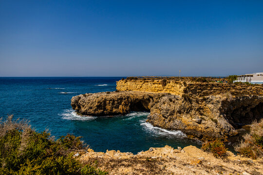 Fototapeta A rugged coastline with steep cliffs overlooks a calm, deep blue sea under a clear sky
