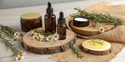 Rustic beauty product mockup with dark amber bottles, beeswax balms, and herbal oils, placed on wooden boards with sprigs of rosemary, chamomile flowers, and burlap fabric.
