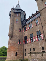 Exterior view of the majestic De Haar Kastel in the Netherlands, showcasing its impressive towers, moats, and red-brick architecture