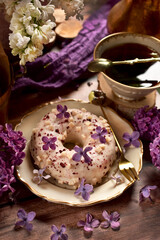 Delicious donut with white chocolate glaze and black berry filling with purple lilac decoration