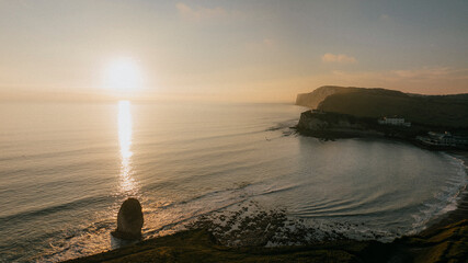 The sun is setting over the ocean, casting a warm glow on the water © Reuben