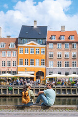Obraz premium Charming waterfront view in Copenhaen with a couple enjoying sunny day by the canal