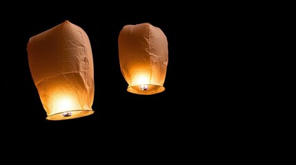 Two glowing sky lanterns ascend into the night sky, symbolizing hope and wishes