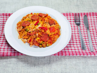 Fine tasty Spanish paella dinner with rice and high quality chorizo sausage on white plate and simple table runner. Mediterranean style dish. Popular food made from premium ingredients.