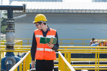 service engineer checking on waste water treatment plant with pump on background. worker working on...