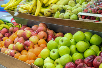 Fruit stand at local market with fresh apples, pears, and bananas on display
