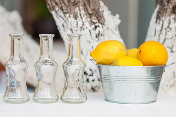 3 Glass Bottles with Lemons in a Metal Bucket - Fresh Lemons, Summer Refreshment, Rustic Beverage Display