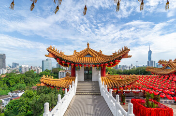 The stunning architecture of Thean Hou Temple, framed by lush greenery, under a vibrant sky. The site is adorned with red lanterns, creating a festive atmosphere