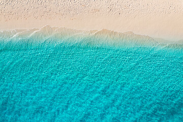 Beautiful bright sea with waves splashing on beach sandy shore. Summer seascape beautiful waves blue sea water in sunny day. Top view from drone. Scenic aerial view amazing tropical nature background