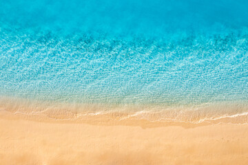 Fototapeta na wymiar Beautiful bright sea with waves splashing on beach sandy shore. Summer seascape beautiful waves blue sea water in sunny day. Top view from drone. Scenic aerial view amazing tropical nature background