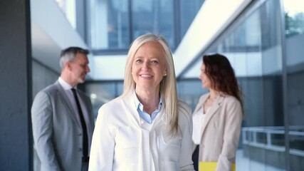 Confident female doctor smiling with colleagues in background