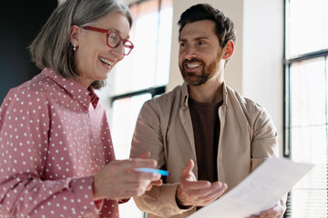 Coworkers discussing and smiling while reviewing documents in the office