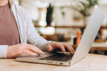 Freelancer working on laptop in cafe, typing on keyboard and using touchpad