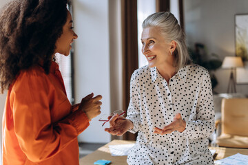 Two businesswomen discussing and smiling during a meeting