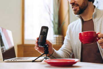 Content creator recording podcast with microphone and laptop drinking coffee