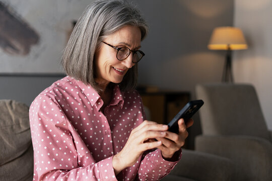 Smiling senior woman using smartphone at home