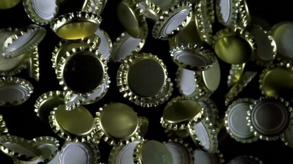 Bottle Caps in Flight. Golden beer bottle caps floating in the air on a black background. Slow Motion - Powered by Adobe