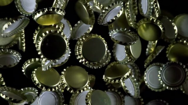 Bottle Caps in Flight. Golden beer bottle caps floating in the air on a black background. Slow Motion