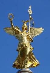 Fototapeta premium Frontal close up of the iconic Goldelse golden angel statue on top of the landmark Siegessäule (Victory Column) on Grosser Stern, Berlin, Germany