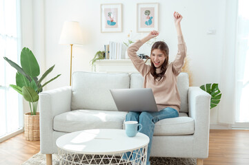 Young Woman Enjoys Working on a Laptop While Sipping Coffee in a Cozy Living Room Setting