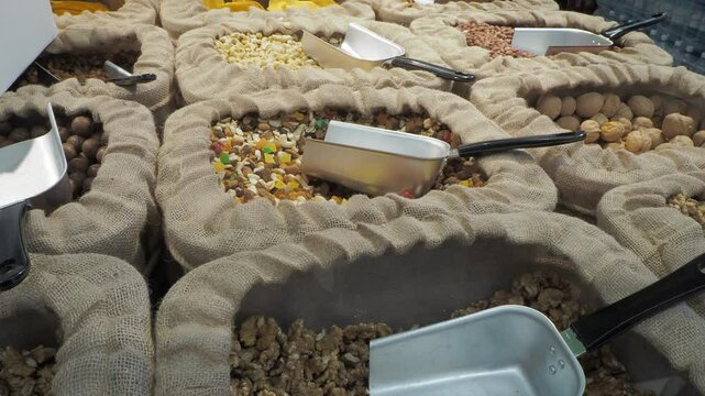 Food trade. Bags with different varieties of nuts, each with a scoop for convenience, so that customers can collect the required amount for themselves. Hand held. Siberia.